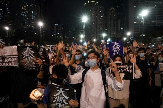 Pessoas gesticulam o popular slogan de protesto 'Cinco demandas, nada menos', enquanto participam de uma vigília no Victoria Park em Hong Kong, após a lembrança anual que tradicionalmente ocorre no parque para marcar a repressão da Praça Tiananmen em 1989.(foto: Yan ZHAO / AFP) Pessoas gesticulam o popular slogan de protesto 'Cinco demandas, nada menos', enquanto participam de uma vigília no Victoria Park em Hong Kong, após a lembrança anual que tradicionalmente ocorre no parque para marcar a repressão da Praça Tiananmen em 1989.(foto: Yan ZHAO / AFP)