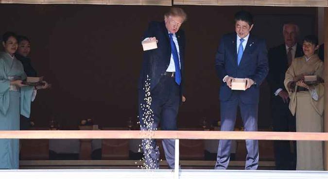 De pé, Trump e o primeiro-ministro japonês Shinzo Abe começaram a jogar pequenas porções da comida, que estava em caixas de madeira, em uma lagoa repleta de carpas koi coloridas, no palácio de Akasaka(foto: Jim Watson/AFP) De pé, Trump e o primeiro-ministro japonês Shinzo Abe começaram a jogar pequenas porções da comida, que estava em caixas de madeira, em uma lagoa repleta de carpas koi coloridas, no palácio de Akasaka(foto: Jim Watson/AFP)