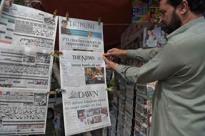 Um vendedor paquistanês organiza jornais matutinos em uma banca um dia depois da eleição geral em Islamabad (foto: Aamir Qureshi/AFP) Um vendedor paquistanês organiza jornais matutinos em uma banca um dia depois da eleição geral em Islamabad (foto: Aamir Qureshi/AFP)