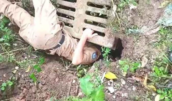 O soldado Mendes projetou de cabeça na boca do bueiro, enquanto um morador do bairro segurava seus pés para que ele também não fosse arrastado pela correnteza(foto: Reprodução/YouTube) O soldado Mendes projetou de cabeça na boca do bueiro, enquanto um morador do bairro segurava seus pés para que ele também não fosse arrastado pela correnteza(foto: Reprodução/YouTube)