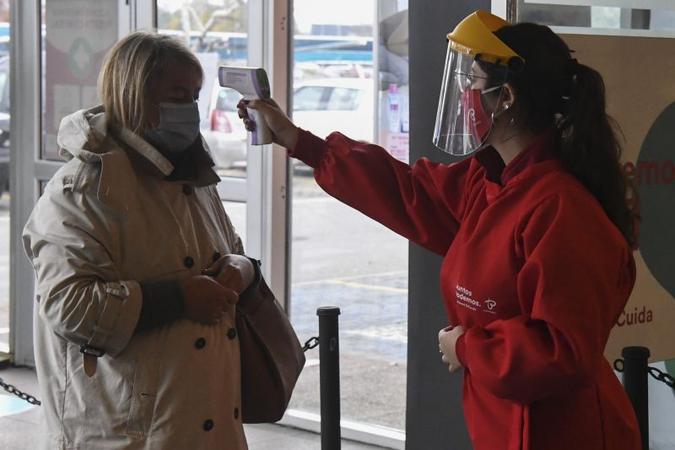 Funcionária de shopping de Montevidéu monitora temperatura de cliente(foto: AFP / PABLO PORCIUNCULA) Funcionária de shopping de Montevidéu monitora temperatura de cliente(foto: AFP / PABLO PORCIUNCULA)
