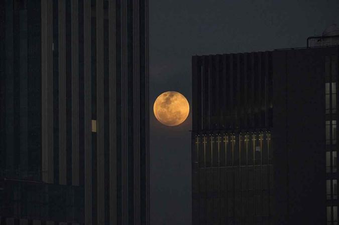 A superlua sobe entre dois prédios de escritórios em Banguecoque em 31 de janeiro de 2018. A população esperavam um eclipse lunar raro que combina três eventos incomuns - uma lua azul, uma super lua e um eclipse total LILLIAN SUWANRUMPHA/ AFP A superlua sobe entre dois prédios de escritórios em Banguecoque em 31 de janeiro de 2018. A população esperavam um eclipse lunar raro que combina três eventos incomuns - uma lua azul, uma super lua e um eclipse total LILLIAN SUWANRUMPHA/ AFP