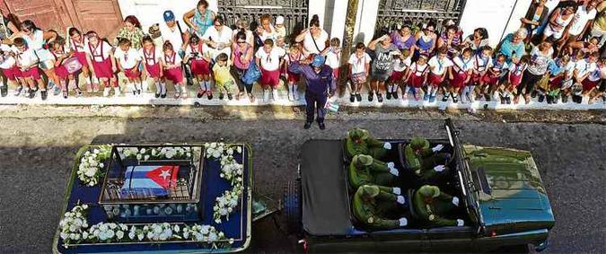 Estudantes e adultos observam, da calçada, a passagem do comboio que carrega as cinzas do ex-presidente Fidel Castro pela cidade de Matanzas: urna foi envolta em redoma de vidro e coberta com a bandeira de Cuba (foto: Ronaldo Schemidt/AFP) Estudantes e adultos observam, da calçada, a passagem do comboio que carrega as cinzas do ex-presidente Fidel Castro pela cidade de Matanzas: urna foi envolta em redoma de vidro e coberta com a bandeira de Cuba (foto: Ronaldo Schemidt/AFP)