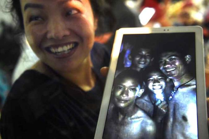 Mulher exibe em tablet foto de meninos preso dentro da caverna: resgate enfrenta série de dificuldades(foto: Lillian Suwanrumpha/AFP) Mulher exibe em tablet foto de meninos preso dentro da caverna: resgate enfrenta série de dificuldades(foto: Lillian Suwanrumpha/AFP)