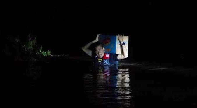 Os habitantes, alguns com água chegando à altura do peito, esforçaram-se ao máximo para alcançar áreas mais elevadas e se refugiar(foto: AFP) Os habitantes, alguns com água chegando à altura do peito, esforçaram-se ao máximo para alcançar áreas mais elevadas e se refugiar(foto: AFP)