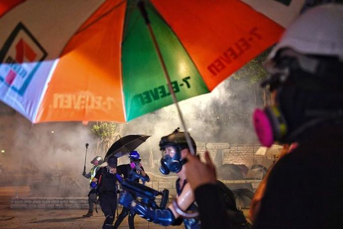 Jovens usam guarda-chuvas para minimizar efeitos do gás lacrimogêneo (foto: Manan Vatsyayana/AFP ) Jovens usam guarda-chuvas para minimizar efeitos do gás lacrimogêneo (foto: Manan Vatsyayana/AFP )