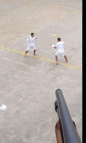 Agente aponta espingarda para dois presos que brigam armados em um dos pátios da Papuda(foto: PDF I/Divulgação) Agente aponta espingarda para dois presos que brigam armados em um dos pátios da Papuda(foto: PDF I/Divulgação)