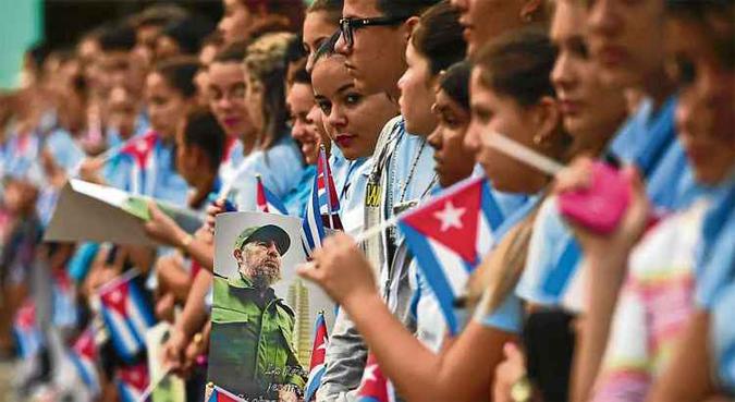 Estudantes aguardam a passagem da urna funerária com as cinzas de Fidel, em Santa Clara: bandeiras nas mãos, fotos do Comandante (abaixo) e muita apreensão (foto: Ronaldo Schemidt/AFP) Estudantes aguardam a passagem da urna funerária com as cinzas de Fidel, em Santa Clara: bandeiras nas mãos, fotos do Comandante (abaixo) e muita apreensão (foto: Ronaldo Schemidt/AFP)