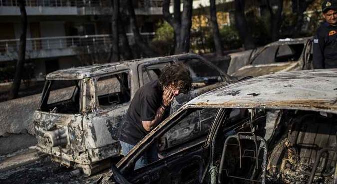 Uma mulher tenta encontrar seu cão após um incêndio na aldeia de Mati, perto de Atenas(foto: Angelos Tzortzinis/AFP ) Uma mulher tenta encontrar seu cão após um incêndio na aldeia de Mati, perto de Atenas(foto: Angelos Tzortzinis/AFP )
