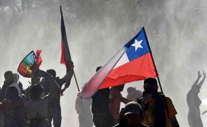 As pessoas nas ruas de Santiago com bandeira nacional chilena contra as políticas econômicas do governo.(foto: Rodrigo Arangua/AFP)