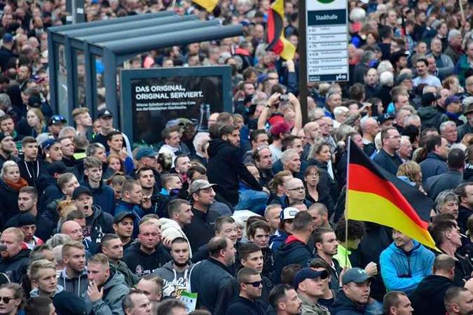 Os manifestantes seguram bandeiras da Alemanha durante um protesto organizado pelo movimento populista de direita Os manifestantes seguram bandeiras da Alemanha durante um protesto organizado pelo movimento populista de direita