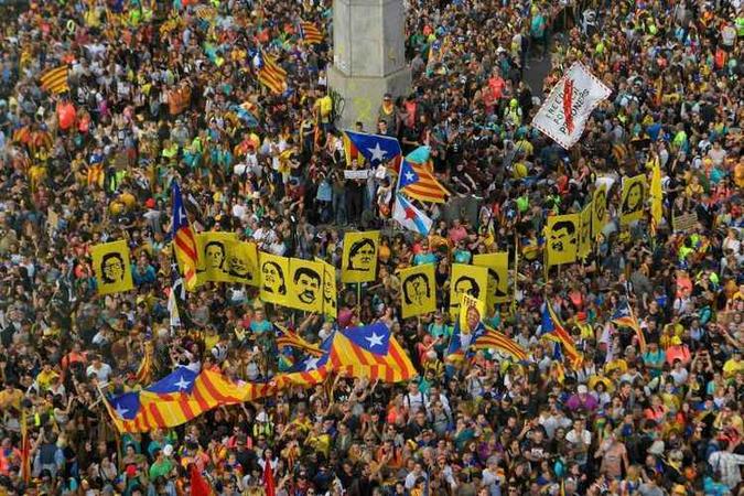 Cartazes com os retratos de líderes separatistas condenados pelo Tribunal Supremo de Madri são exibidos pela multidão, além da bandeira Cartazes com os retratos de líderes separatistas condenados pelo Tribunal Supremo de Madri são exibidos pela multidão, além da bandeira