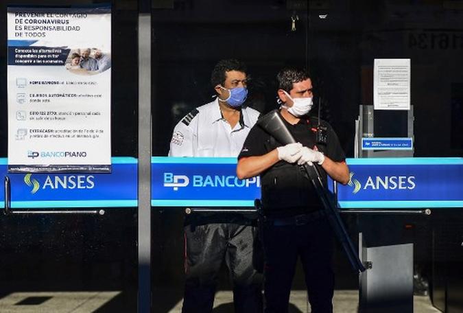 Membros de uma equipe de segurança privada vigiam a entrada de um banco antes do horário de funcionamento, no município de Jose C Paz, província de Buenos Aires, em 4 de abril de 2020, durante o bloqueio na Argentina para retardar a disseminação do novo coronavírus.(foto: Ronaldo SCHEMIDT / AFP) Membros de uma equipe de segurança privada vigiam a entrada de um banco antes do horário de funcionamento, no município de Jose C Paz, província de Buenos Aires, em 4 de abril de 2020, durante o bloqueio na Argentina para retardar a disseminação do novo coronavírus.(foto: Ronaldo SCHEMIDT / AFP)