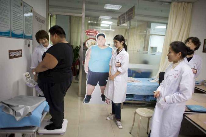 Observado por profissionais de saúde, adolescente chinês se pesa em um consultório de Pequim: demonstração de afeto é determinante para o paciente(foto: Alain Jocard/AFP - 12/4/19 ) Observado por profissionais de saúde, adolescente chinês se pesa em um consultório de Pequim: demonstração de afeto é determinante para o paciente(foto: Alain Jocard/AFP - 12/4/19 )
