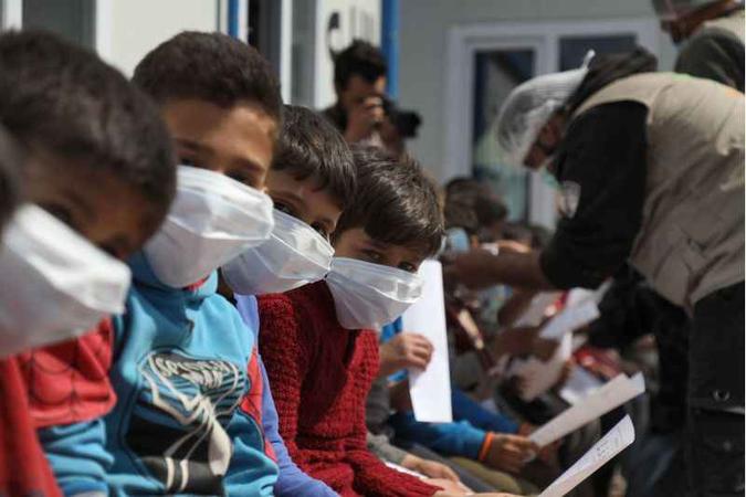 Meninos sírios, com máscaras, recebem orientações de prevenção em centro de refugiados na Turquia: diagnóstico é mais difícil nos pequenos(foto: FP / AAREF WATAD) Meninos sírios, com máscaras, recebem orientações de prevenção em centro de refugiados na Turquia: diagnóstico é mais difícil nos pequenos(foto: FP / AAREF WATAD)