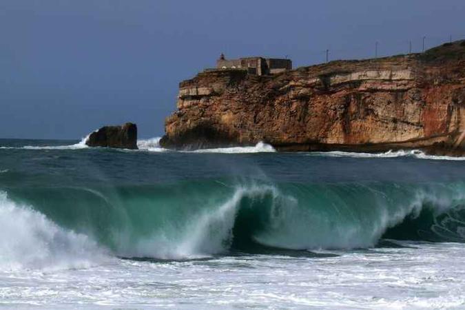 O histórico Forte de Nazaré, na praia dos surfistas: altas ondas O histórico Forte de Nazaré, na praia dos surfistas: altas ondas