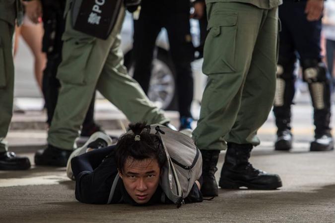 Ativista algemado diante de membros das forças de segurança: homem com bandeira pró-independência foi preso sob nova legislação(foto: AFP / DALE DE LA REY) Ativista algemado diante de membros das forças de segurança: homem com bandeira pró-independência foi preso sob nova legislação(foto: AFP / DALE DE LA REY)