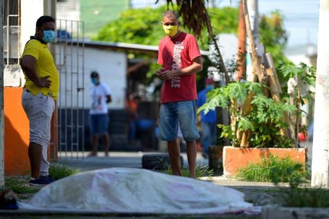 Nesta foto de arquivo tirada em 03 de abril de 2020, as pessoas olham para um corpo que ficou deitado por três dias fora de uma clínica em Guayaquil, Equador. (foto: Str / Marcos Pin / AFP) Nesta foto de arquivo tirada em 03 de abril de 2020, as pessoas olham para um corpo que ficou deitado por três dias fora de uma clínica em Guayaquil, Equador. (foto: Str / Marcos Pin / AFP)