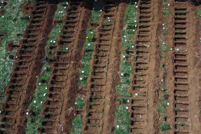 Dezenas de covas abertas em Vila Formosa, em São Paulo, e trabalhadores do cemitério: pandemia mudou a rotina dos campos e das cerimônias de despedida (foto: AFP / NELSON ALMEIDA ) Dezenas de covas abertas em Vila Formosa, em São Paulo, e trabalhadores do cemitério: pandemia mudou a rotina dos campos e das cerimônias de despedida (foto: AFP / NELSON ALMEIDA )