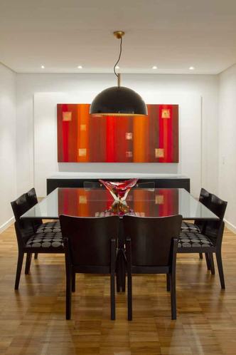 O grande quadro na sala de jantar, projetada pela arquiteta Gislaine Garonce, é a peça que mais chama a atenção no espaço. Além de trazer uma sensação de calor e conforto, as cores fortes dão personalidade ao ambiente de paredes brancas. (foto: Clausem Bonifácio/ Divulgação) O grande quadro na sala de jantar, projetada pela arquiteta Gislaine Garonce, é a peça que mais chama a atenção no espaço. Além de trazer uma sensação de calor e conforto, as cores fortes dão personalidade ao ambiente de paredes brancas. (foto: Clausem Bonifácio/ Divulgação)